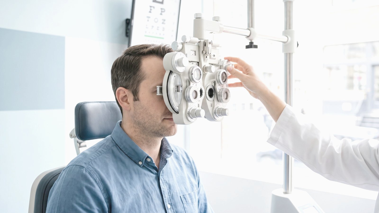 Oferta Mężczyzna patrzy przez foropter podczas badania wzroku u optometrysty – ilustracja